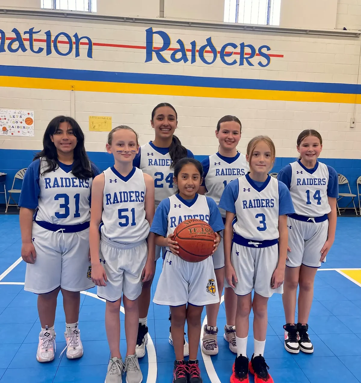 The Reformation Raiders girls basketball team in uniform on the gym floor