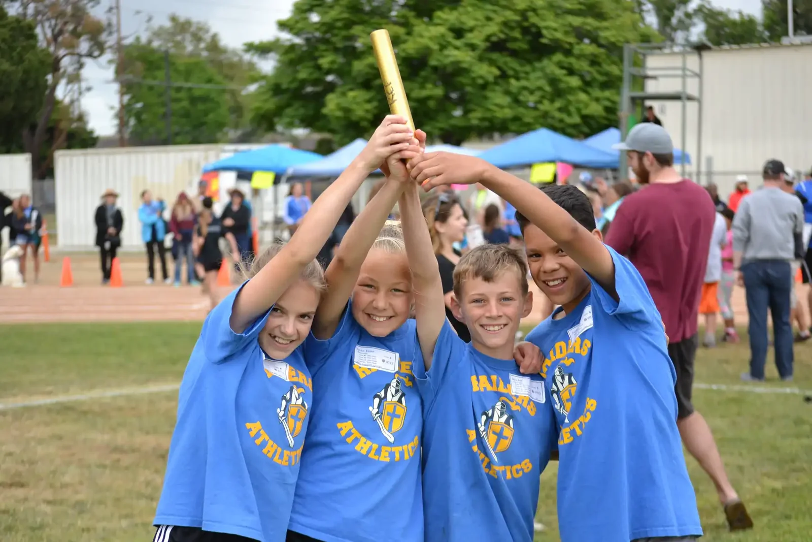 Three Reformation students in blue shirts celebrating at the track and field meet